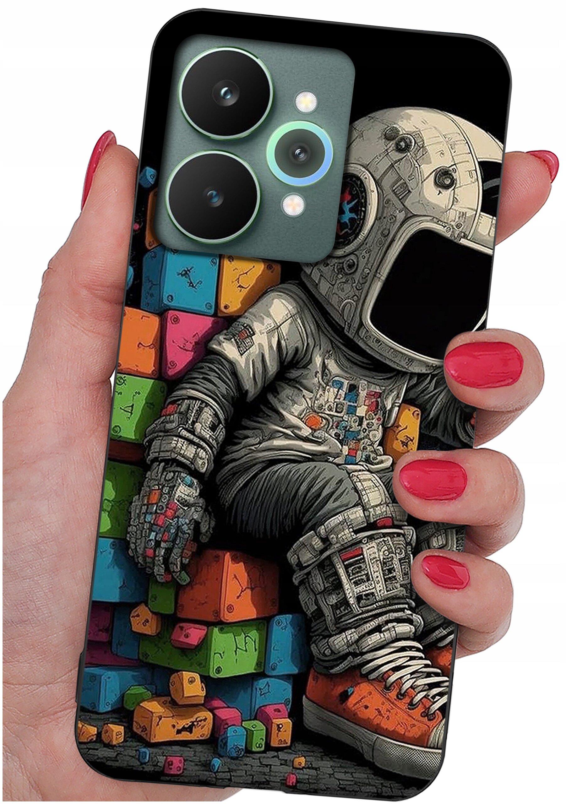 Etui na telefon z kolorowym wzorem przedstawiającym astronautę siedzącego na klockach. Etui trzymane jest w dłoni z pomalowanymi na czerwono paznokciami.