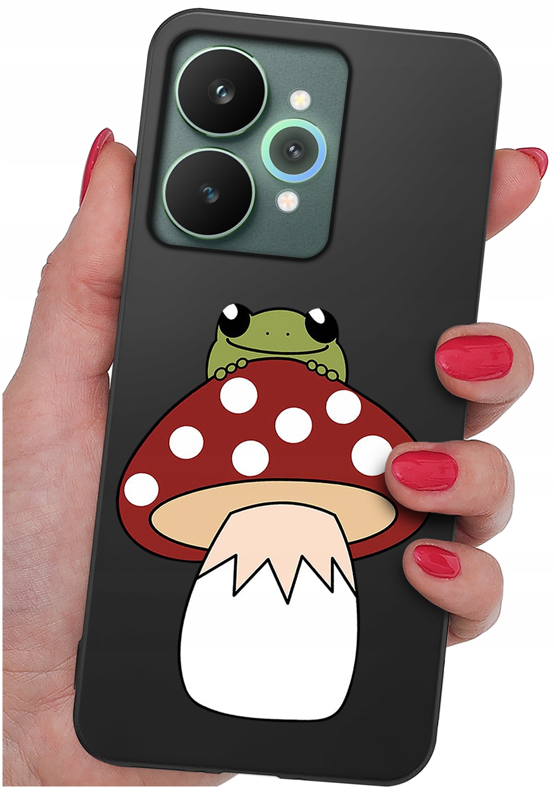 Etui na telefon z grafiką przedstawiającą żabę siedzącą na czerwonym muchomorze z białymi kropkami. Etui jest trzymane w dłoni z pomalowanymi na czerwono paznokciami.