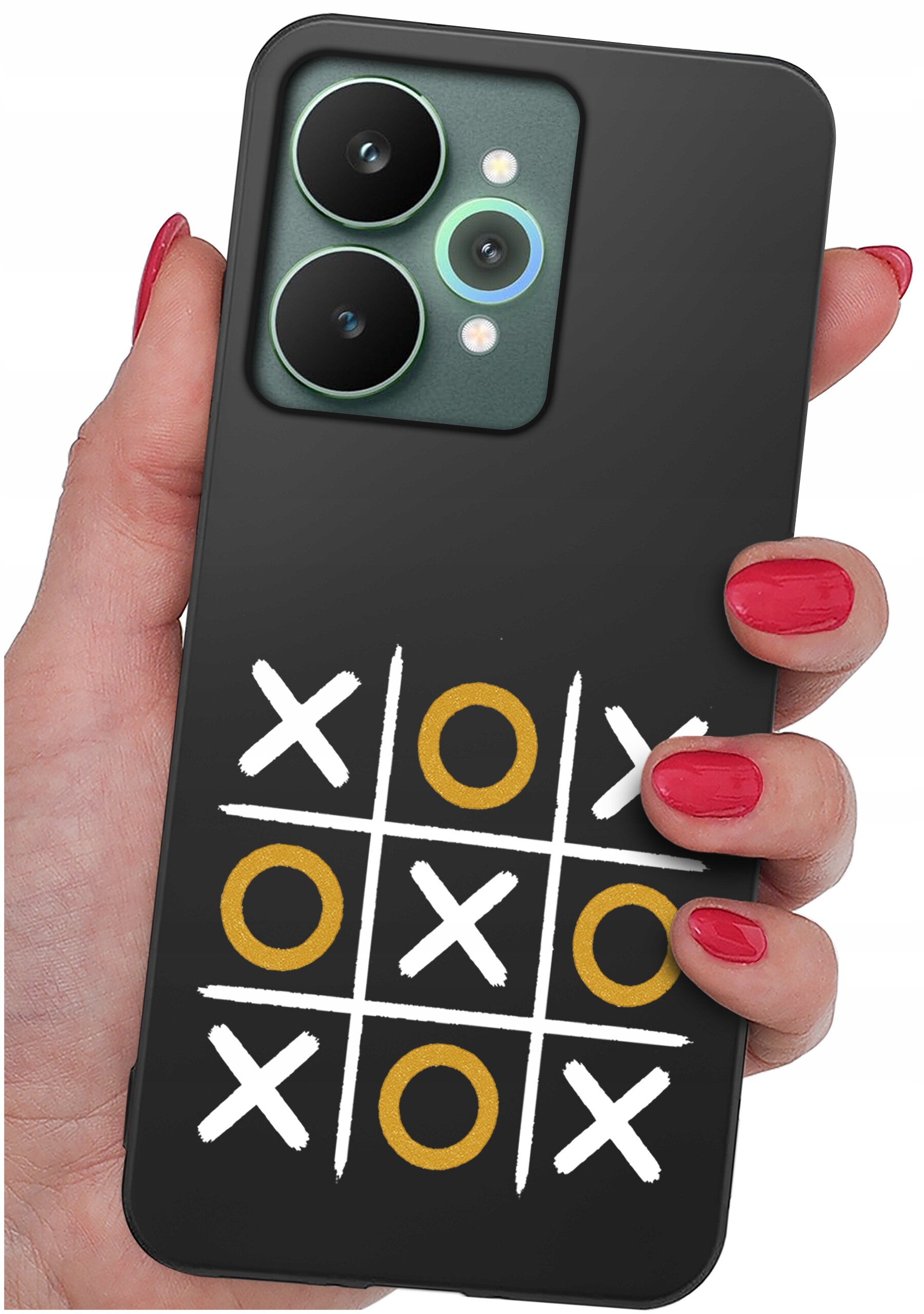Czarna obudowa telefonu z wzorem gry w kółko i krzyżyk, gdzie kółka są złote, a krzyżyki białe. Obudowa jest trzymana w dłoni z pomalowanymi na czerwono paznokciami.
