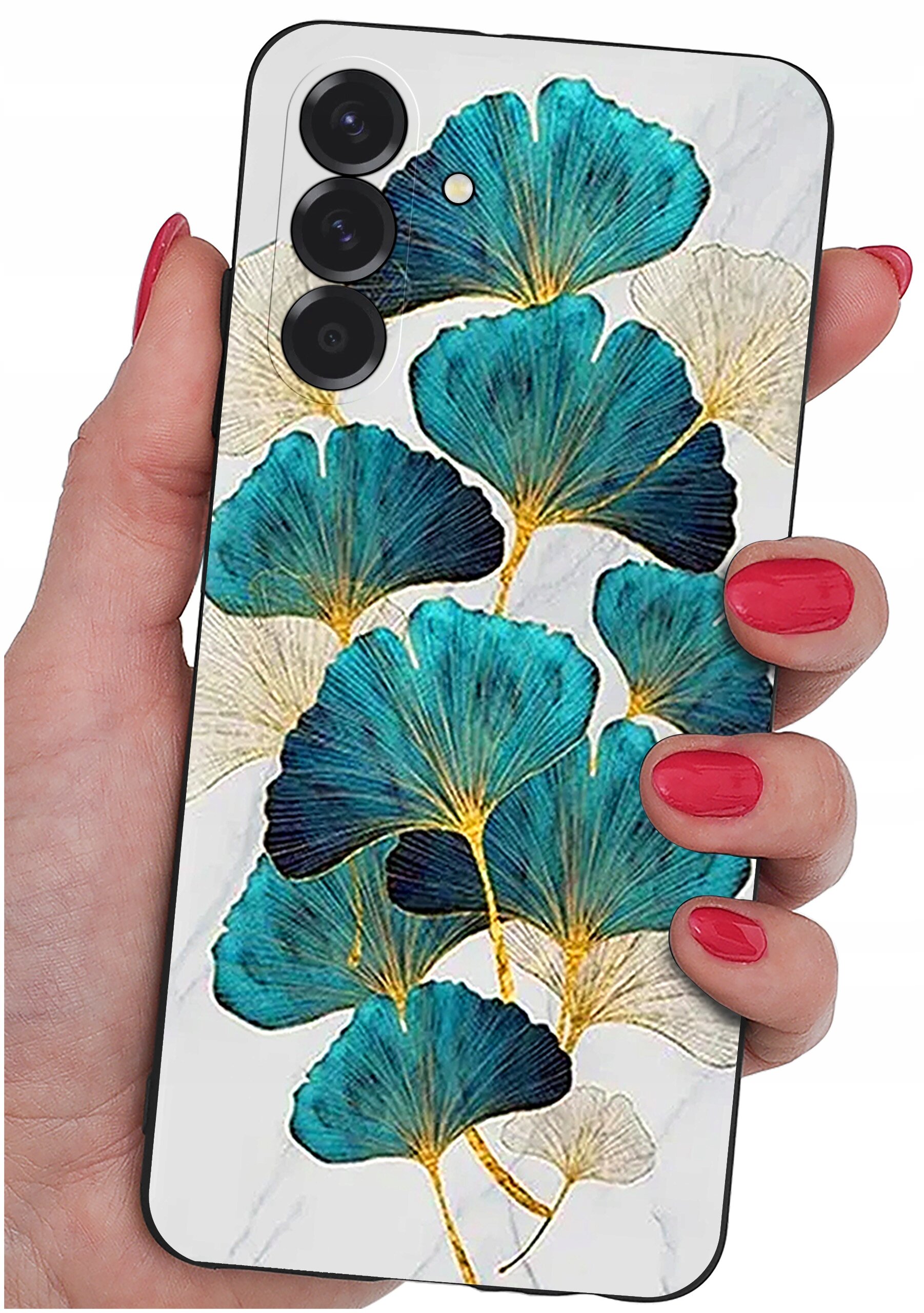 Etui na telefon z wzorem liści w odcieniach niebieskiego i złotego, trzymane w dłoni z pomalowanymi na czerwono paznokciami. Widoczne są trzy obiektywy aparatu na tylnej części telefonu.