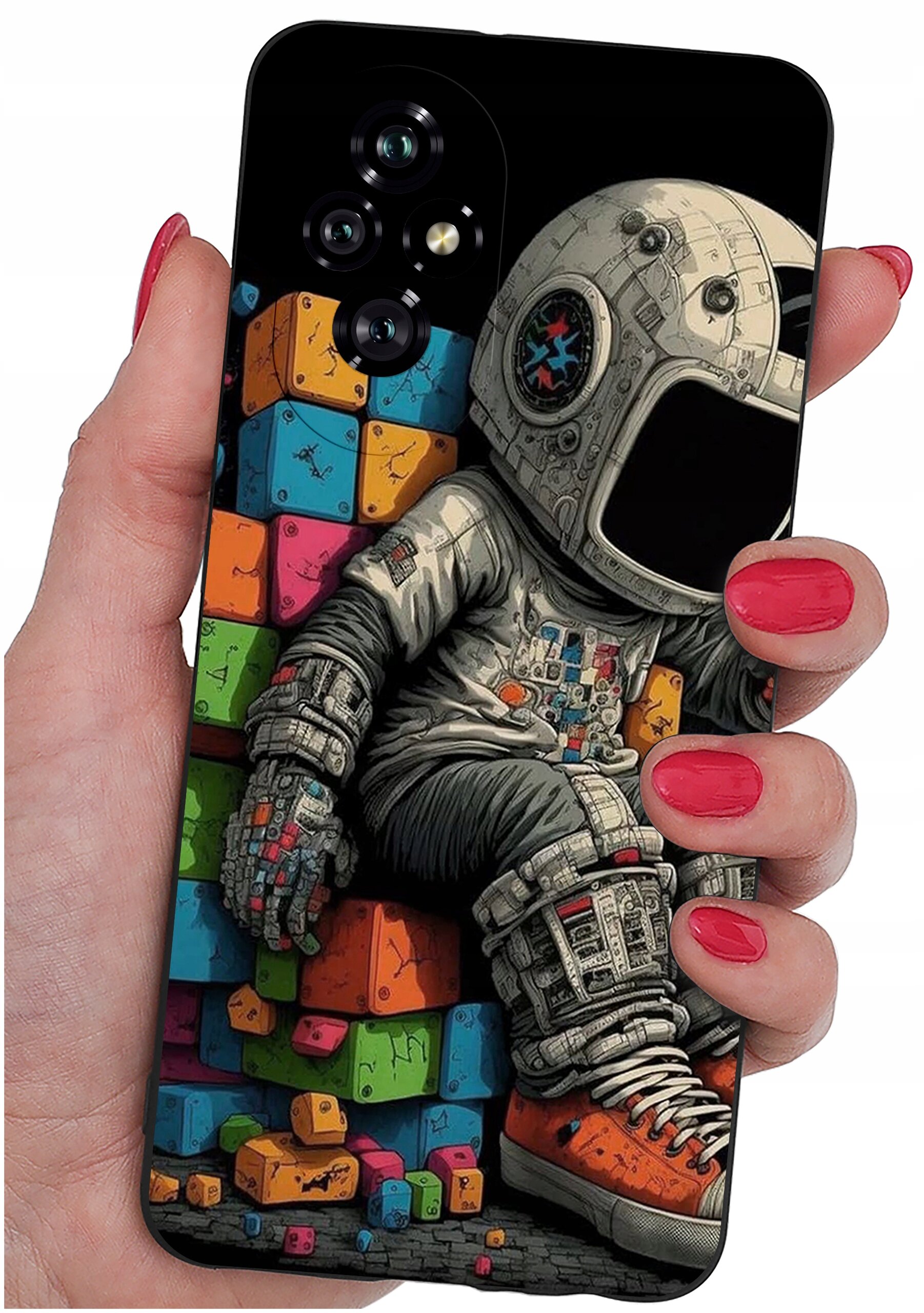 Etui na telefon z kolorowym nadrukiem przedstawiającym astronautę siedzącego na tle klocków. Etui trzymane jest w dłoni z pomalowanymi na czerwono paznokciami.