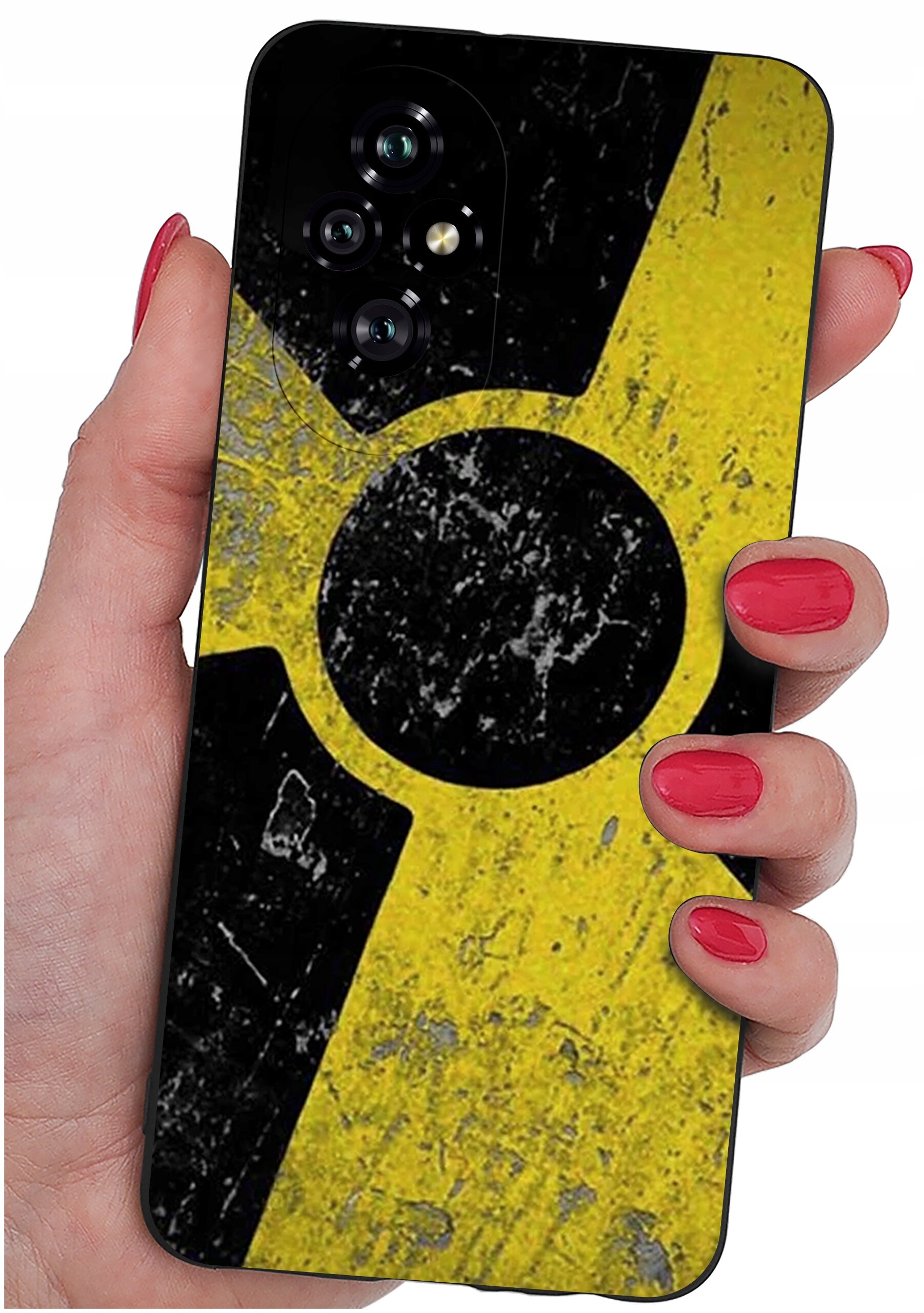 Osoba trzyma telefon z etui o wzorze przypominającym symbol radioaktywności w kolorach żółtym i czarnym. Etui ma matowe wykończenie i widoczne są trzy obiektywy aparatu.