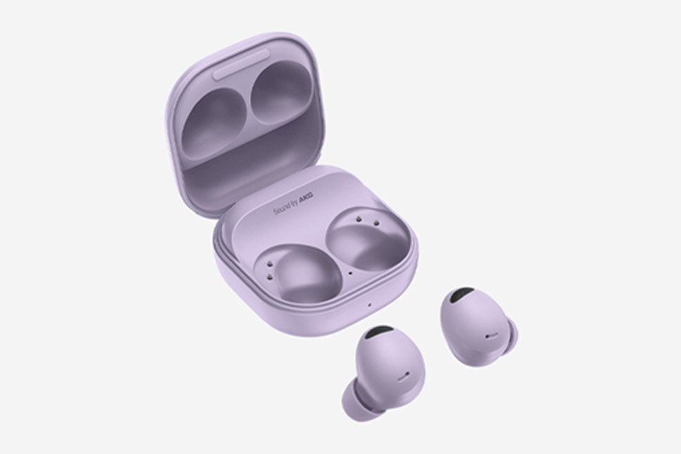 Na obrazie widoczne są bezprzewodowe słuchawki douszne w kolorze fioletowym wraz z otwartym etui ładującym. Na etui znajduje się napis \'Sound by AKG\'.