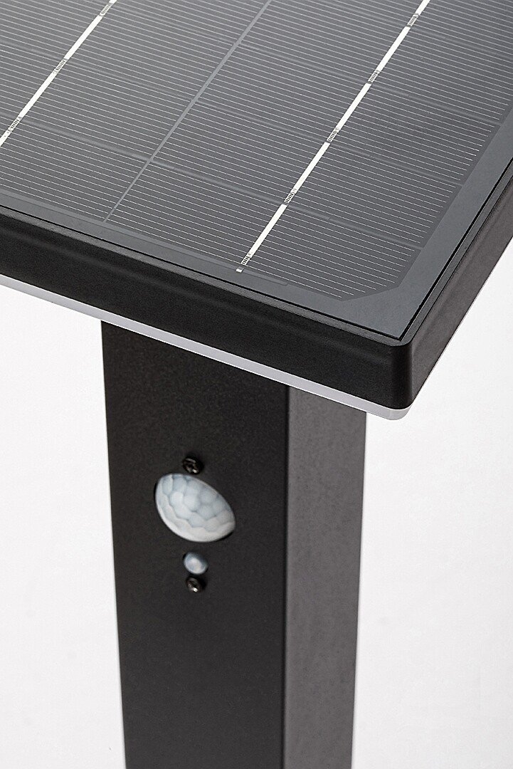 Czarna lampa solarna ogrodowa z panelem słonecznym na górze i czujnikiem ruchu na pionowej części obudowy.