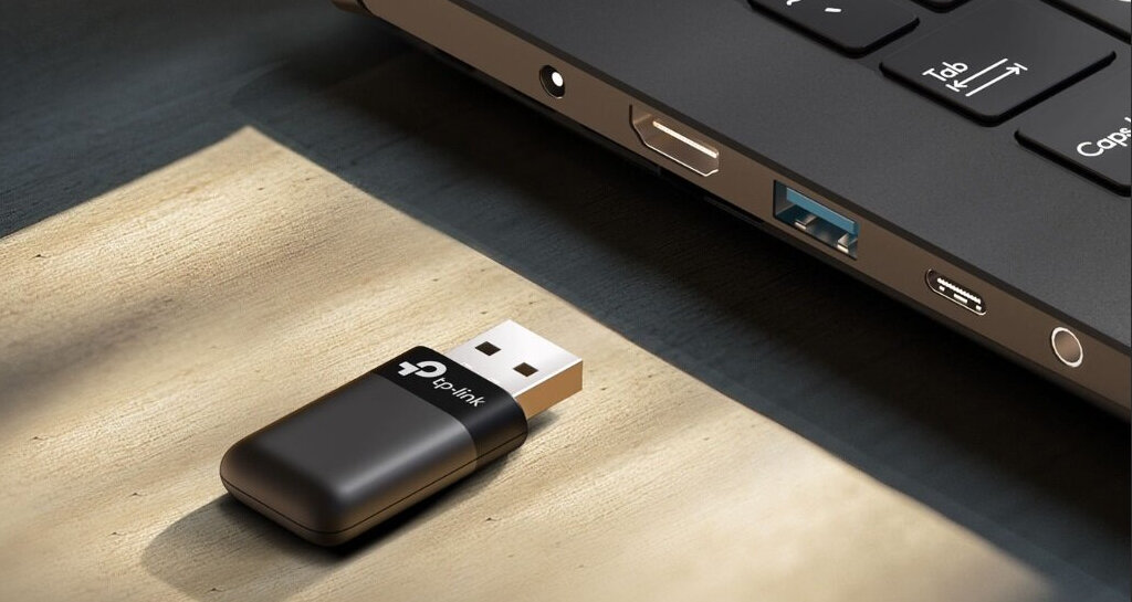 Karta sieciowa TP-LINK Archer TX50U przy porcie USB laptopa.