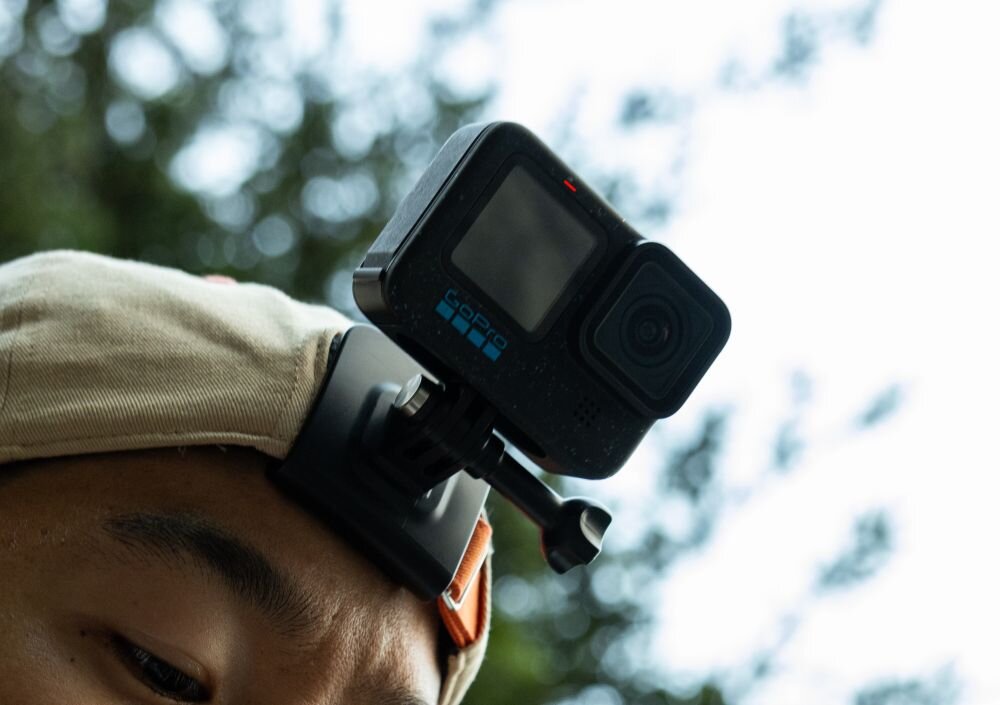 Osoba nosi kamerę sportową zamontowaną na czapce. Na kamerze widoczne jest logo \'GoPro\'.