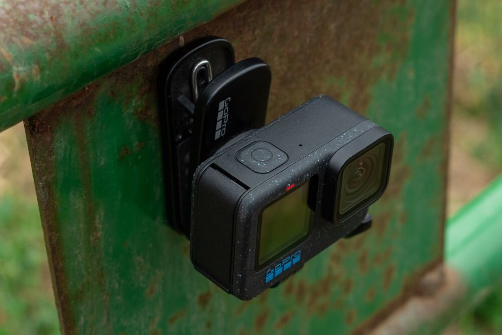 Kamera sportowa zamontowana na metalowej powierzchni za pomocą uchwytu. Na uchwycie widoczne jest logo \'GOPRO\'.
