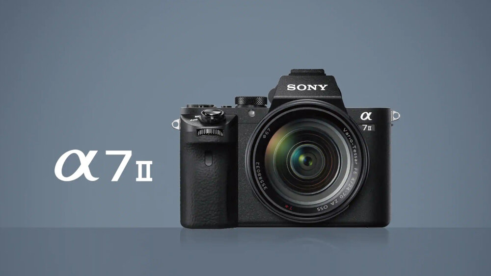 Na obrazie widoczny jest czarny aparat fotograficzny z logo \'SONY\' nad obiektywem. Obok aparatu znajduje się tekst \'α 7 II\'.