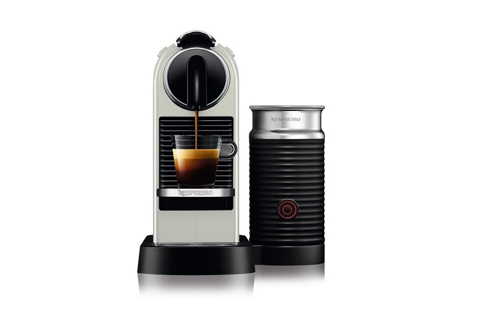 Na obrazie widoczny jest ekspres do kawy z filiżanką, do której nalewana jest kawa, oraz spieniacz do mleka. Na ekspresie i spieniaczu widnieje logo \'Nespresso\'.