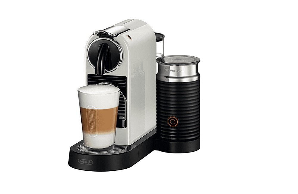 Na obrazie widoczny jest biały ekspres do kawy z filiżanką kawy z mleczną pianką. Obok ekspresu znajduje się czarny spieniacz do mleka z napisem \'NESPRESSO\'.
