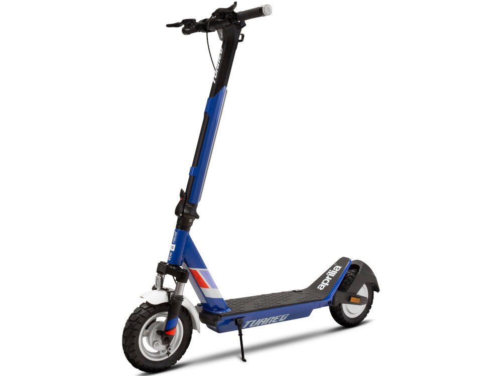 Na obrazie widoczna jest granatowa hulajnoga elektryczna z białymi i czerwonymi akcentami. Na podeście znajduje się napis \'Tuareg\', a na błotniku widnieje logo \'aprilia\'.