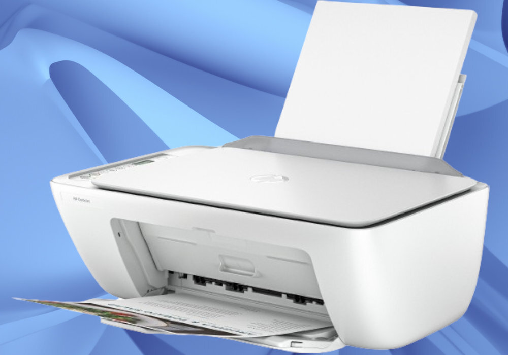 Białe urządzenie wielofunkcyjne z otwartą tacą na papier i widocznym wydrukiem. Na obudowie znajduje się logo HP oraz napis \'HP DeskJet\'.