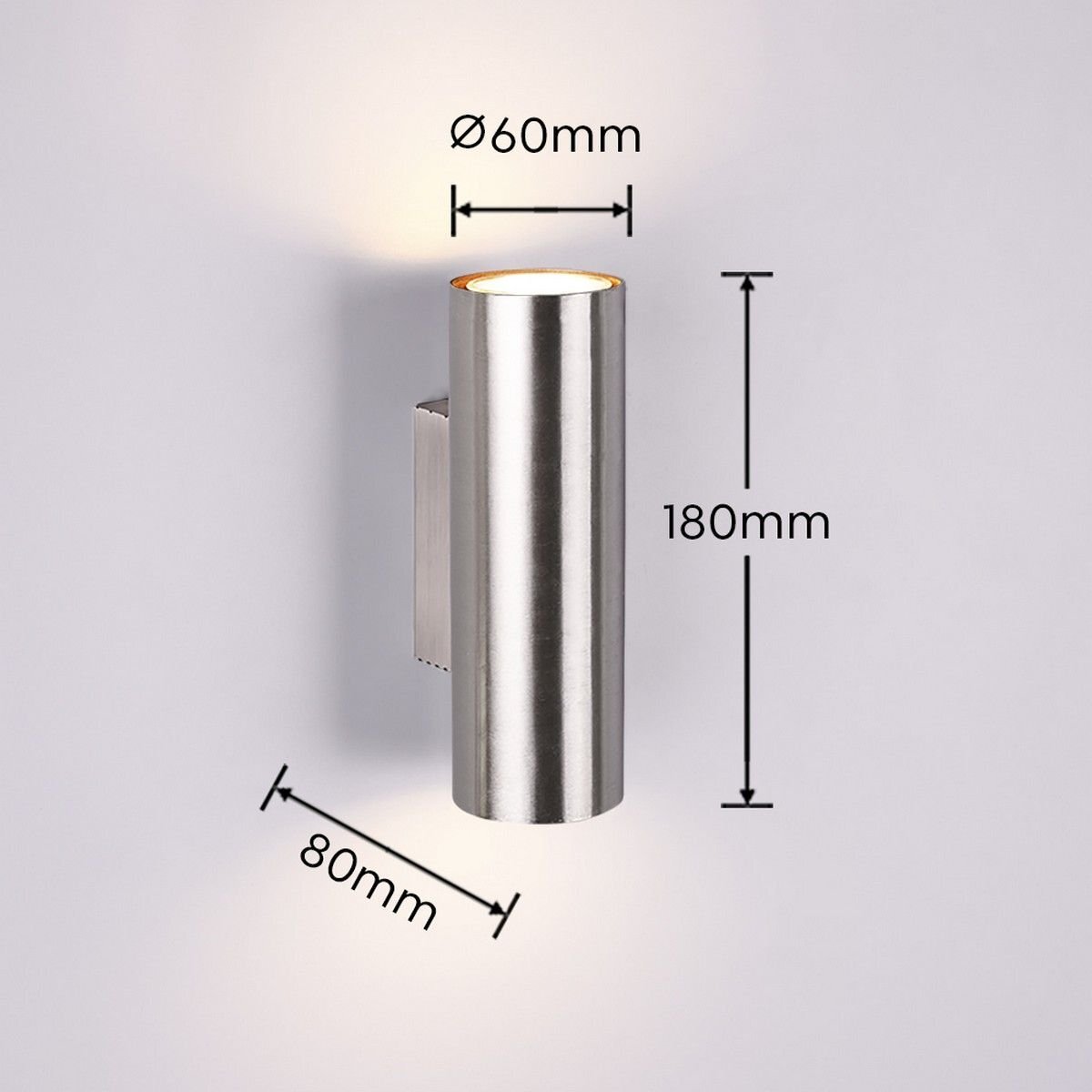 Na obrazie widoczna jest metalowa lampa ścienna o cylindrycznym kształcie z wymiarami: średnica 60mm, wysokość 180mm, głębokość 80mm. Lampa emituje światło zarówno w górę, jak i w dół.