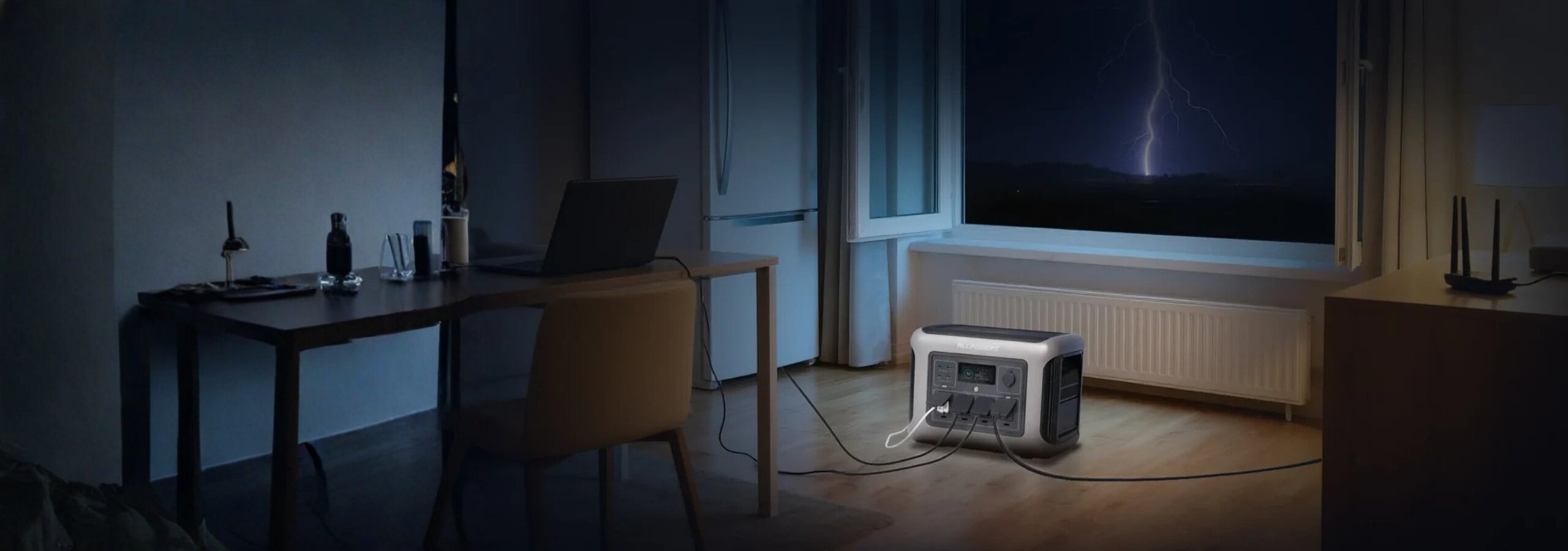 W pokoju nocą stoi przenośna stacja zasilania podłączona do laptopa na biurku. Za oknem widać błyskawicę na ciemnym niebie.