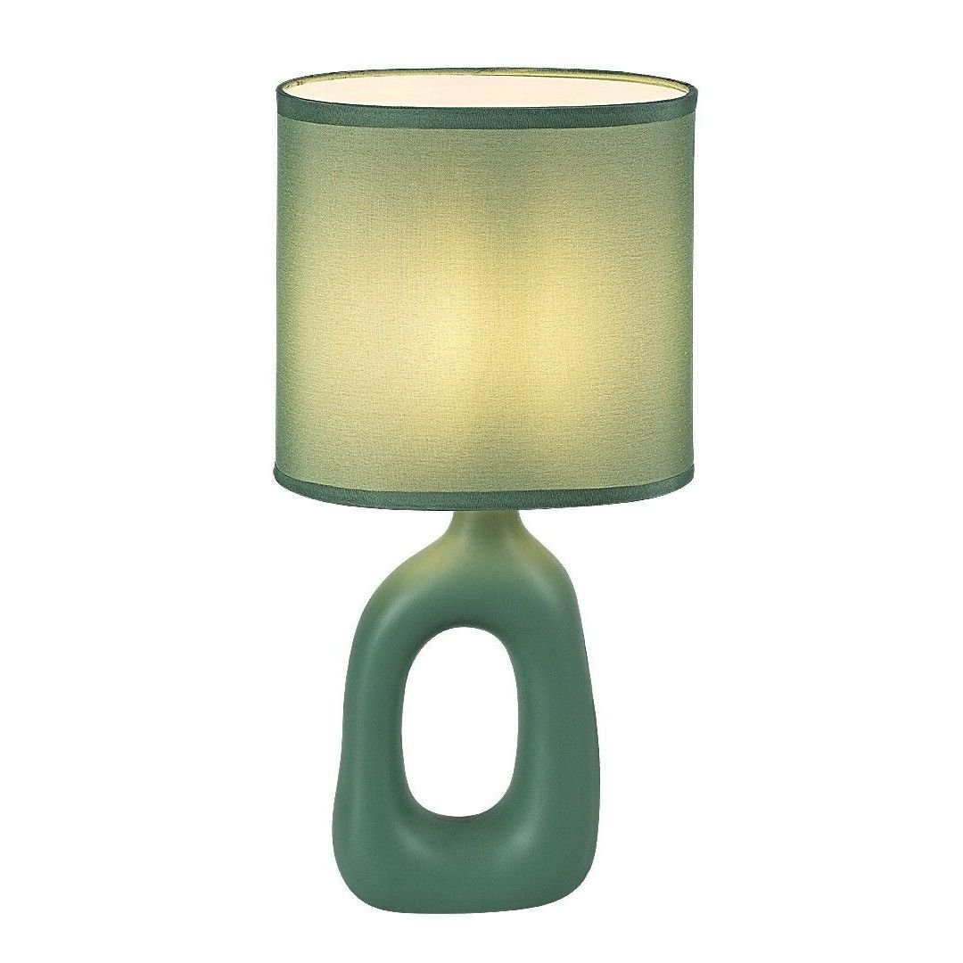 Stylowa lampa nocna z zielonym, owalnym kloszem i podstawą o nowoczesnym kształcie z otworem pośrodku. Lampa emituje ciepłe, rozproszone światło.
