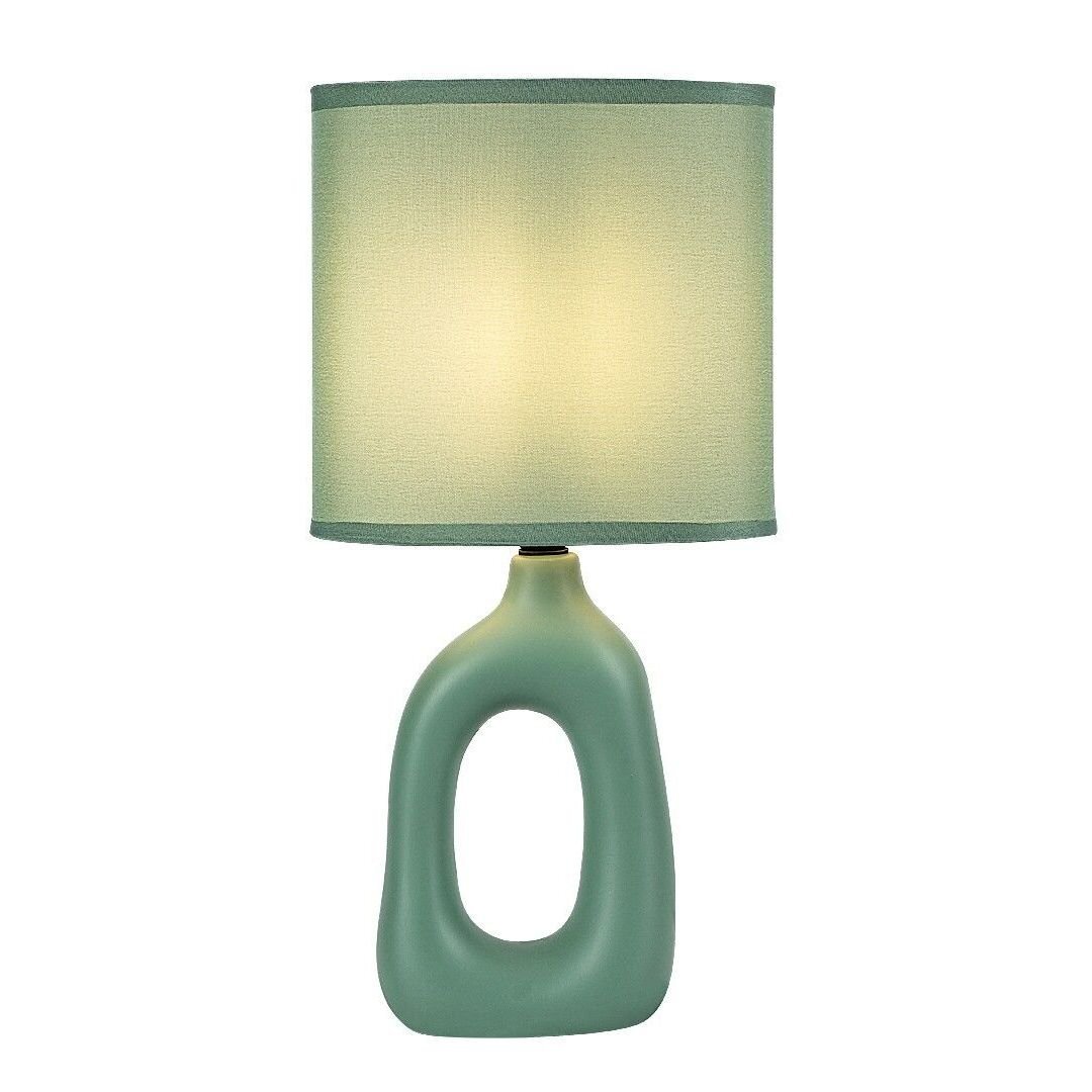 Stylowa lampa nocna z zielonym, owalnym kloszem i podstawą o nowoczesnym kształcie. Lampa emituje ciepłe, rozproszone światło.