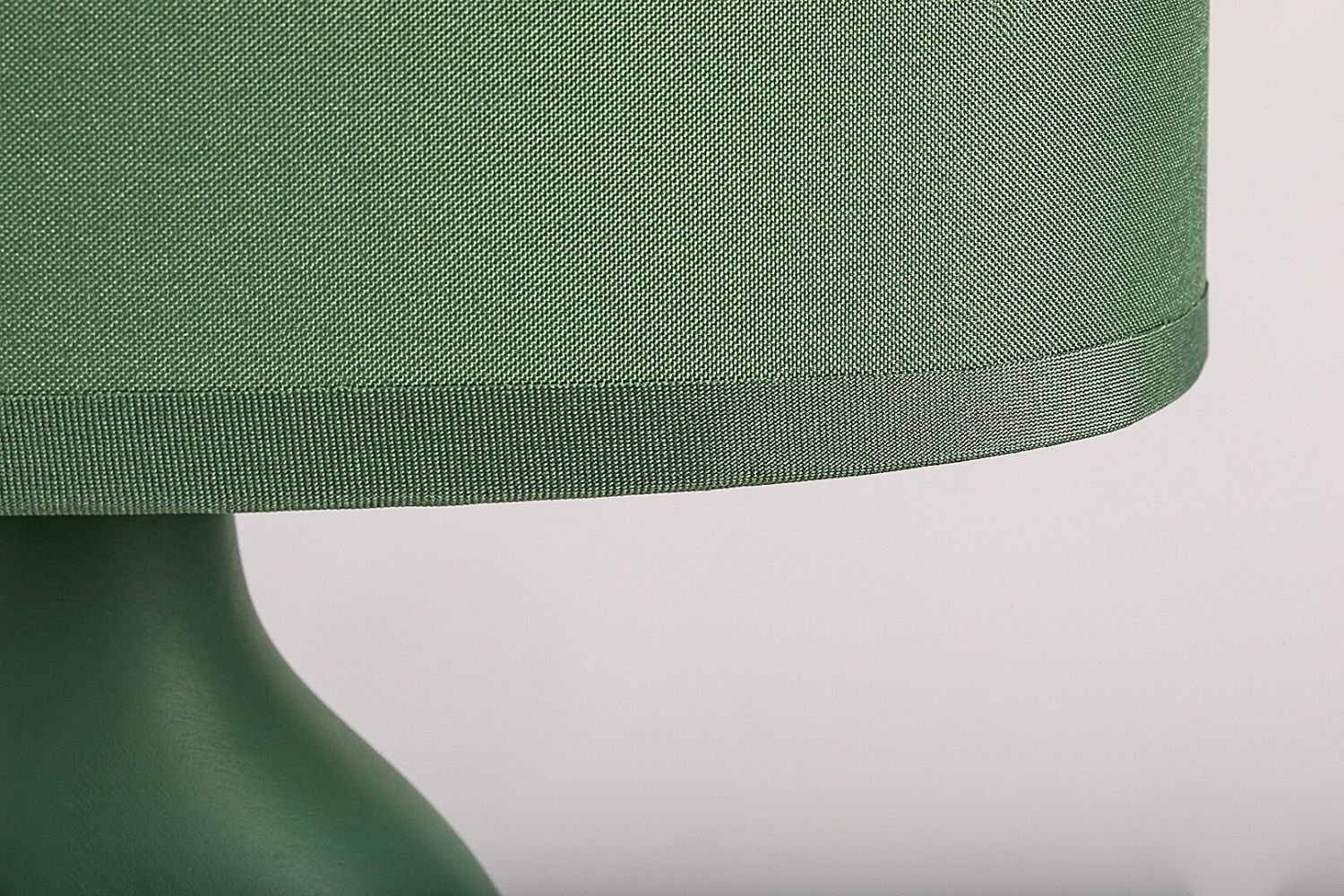 Zbliżenie na zielony abażur lampy z teksturowanym materiałem i gładką podstawą w tym samym kolorze.