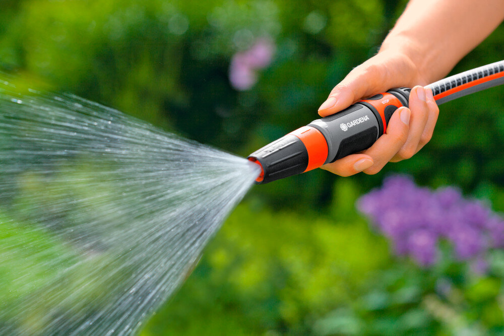 Zraszacz prosty GARDENA zestaw 18296-20 ogród rośliny rozmyte tło osoba trzyma zraszacz w dłoni podlewa rośliny konstrukcja końcówki dyszy uniemożliwia jej wypadnięcie i zgubienie funkcja ochrony przed mrozem trwałość urządzenia eliminują ryzyko uszkodzeń