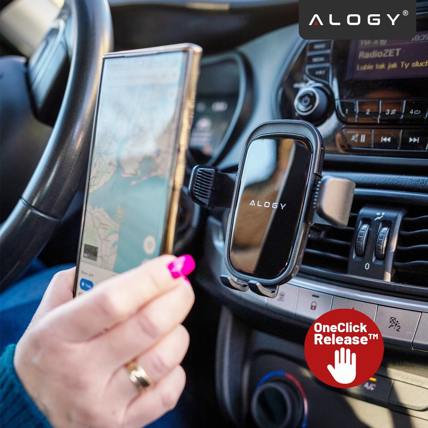 Wnętrze samochodu z zamontowanym uchwytem na telefon marki Alogy na kratce wentylacyjnej. Na ekranie radia widoczny jest napis \'RadioZET\', a na uchwycie znajduje się logo \'Alogy\'.