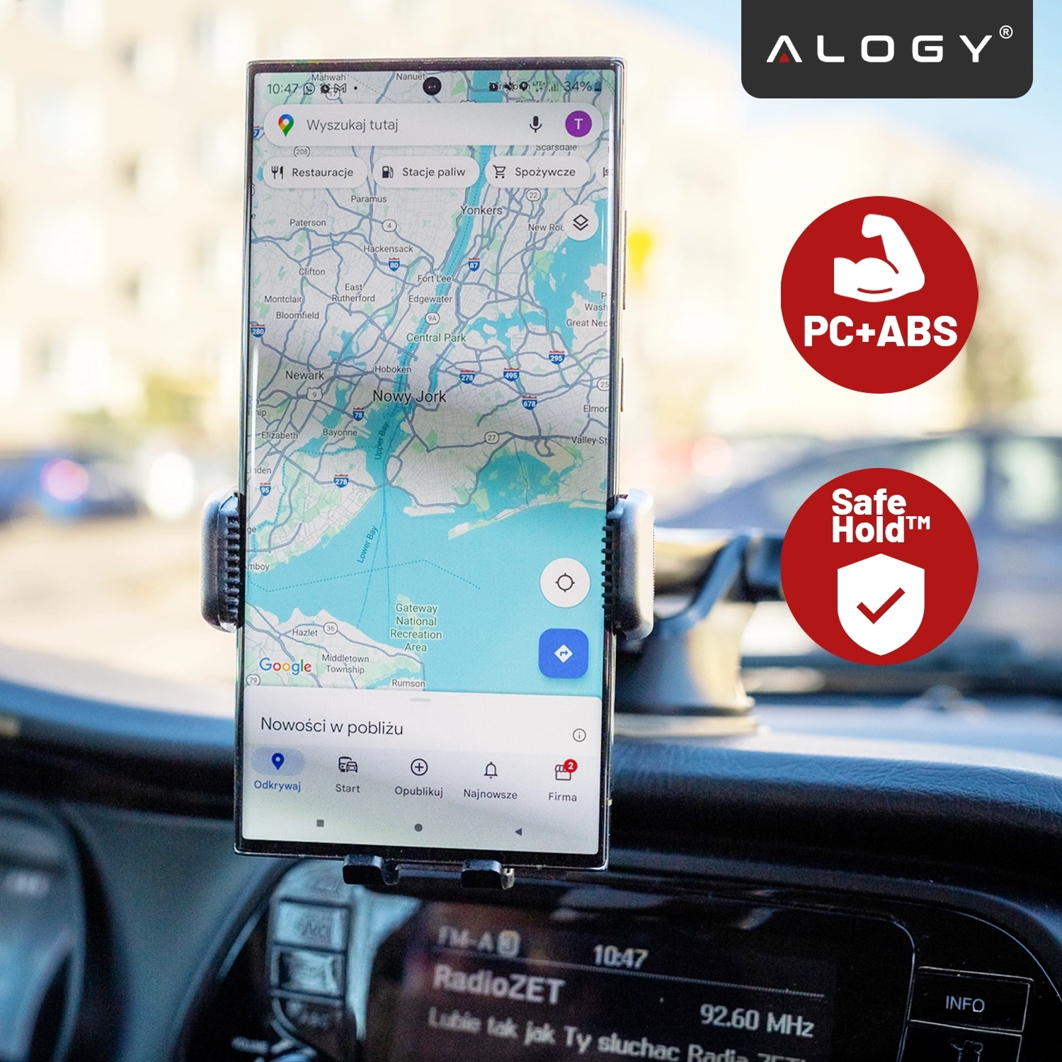 Telefon zamocowany w uchwycie samochodowym wyświetla mapę Nowego Jorku. Widoczne są logo \'Alogy\' oraz ikony z napisami \'PC+ABS\' i \'Safe Hold™\'.