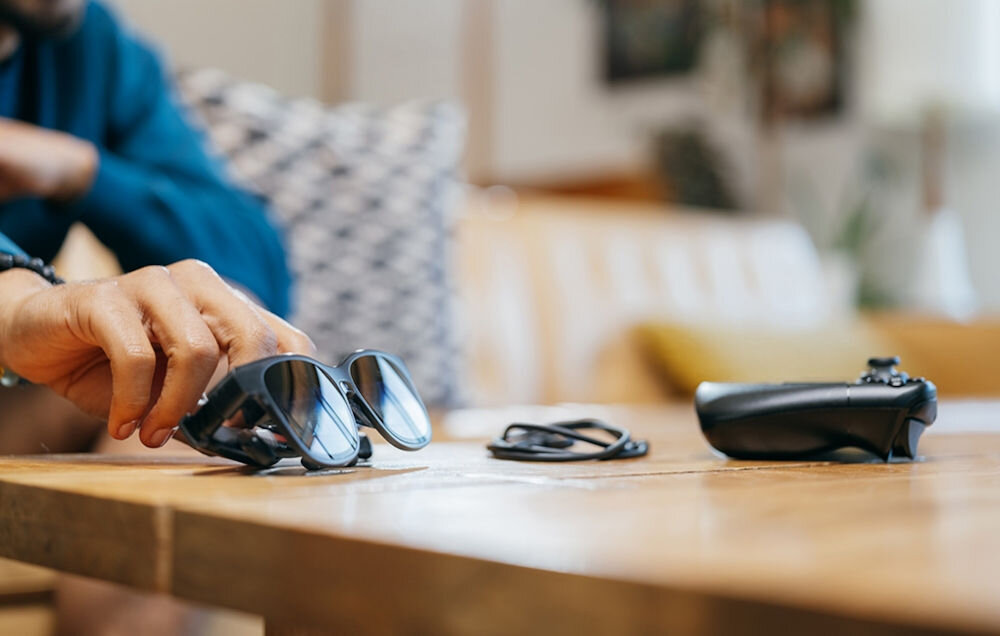 Okulary VITURE XR Luma Pro Czarny prezentacja pada kabla oraz okularów z ręką na nich na stole zdalne granie Nintendo Switch komputer smartfon rozgrywka bez kompromisów