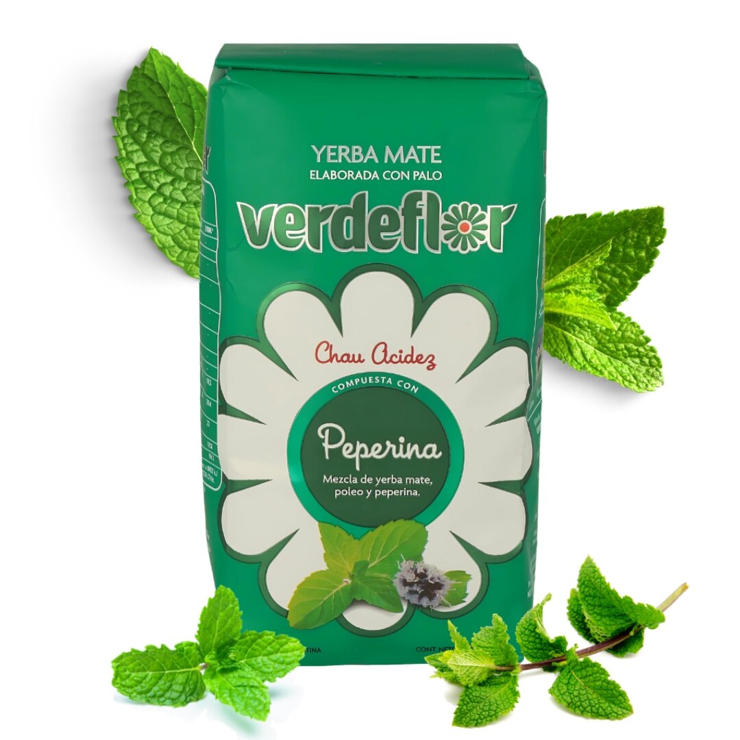 Opakowanie Yerba Mate Verdeflor Peperina 0,5kg w zielonym kolorze z białym kwiatowym wzorem i napisem \'Chau Acidez\'. W tle widoczne są liście mięty.