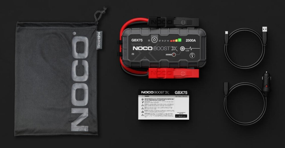 Na czarnym tle znajduje się urządzenie rozruchowe z napisem \'NOCO Boost X GBX75 2500A\', dwa kable USB, kabel z wtykiem do zapalniczki samochodowej, instrukcja oraz czarny worek z logo \'NOCO\'.
