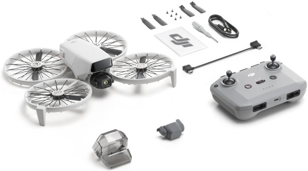 Na obrazie znajduje się dron z czterema osłoniętymi śmigłami, kontroler, dodatkowe akcesoria oraz kabel. Widoczne jest logo DJI na kontrolerze i na kartce papieru.