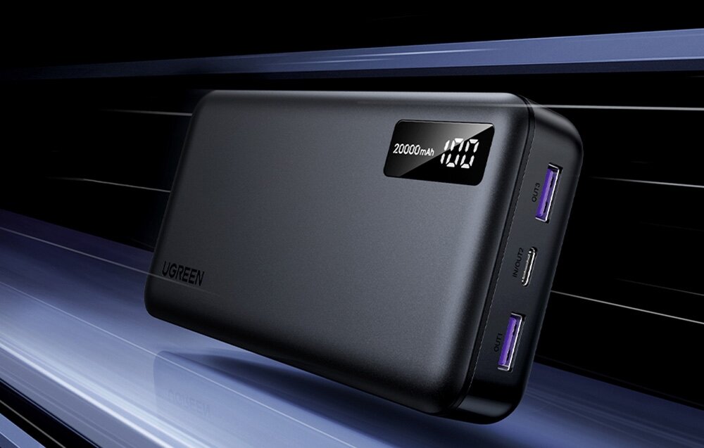 Powerbank UGREEN PB312 20000 mAh - Powerbank Ugreen 20000 mAh z wyświetlaczem LED i trzema portami USB leżący na gładkiej, błyszczącej powierzchni.