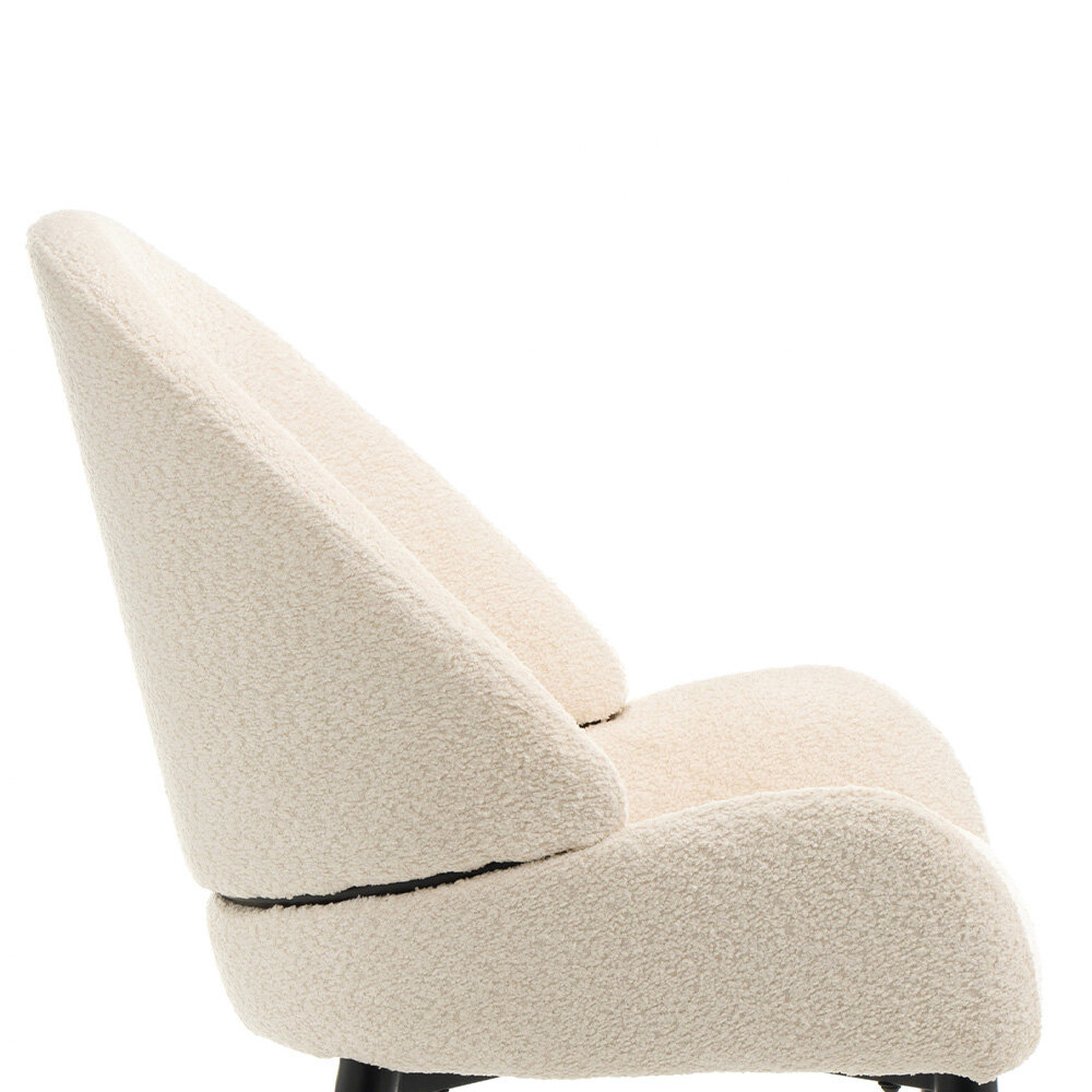 Krzesło tapicerowane w kolorze beżowym z materiału boucle, o eleganckim i nowoczesnym designie. Posiada czarne nogi i wyprofilowane oparcie.