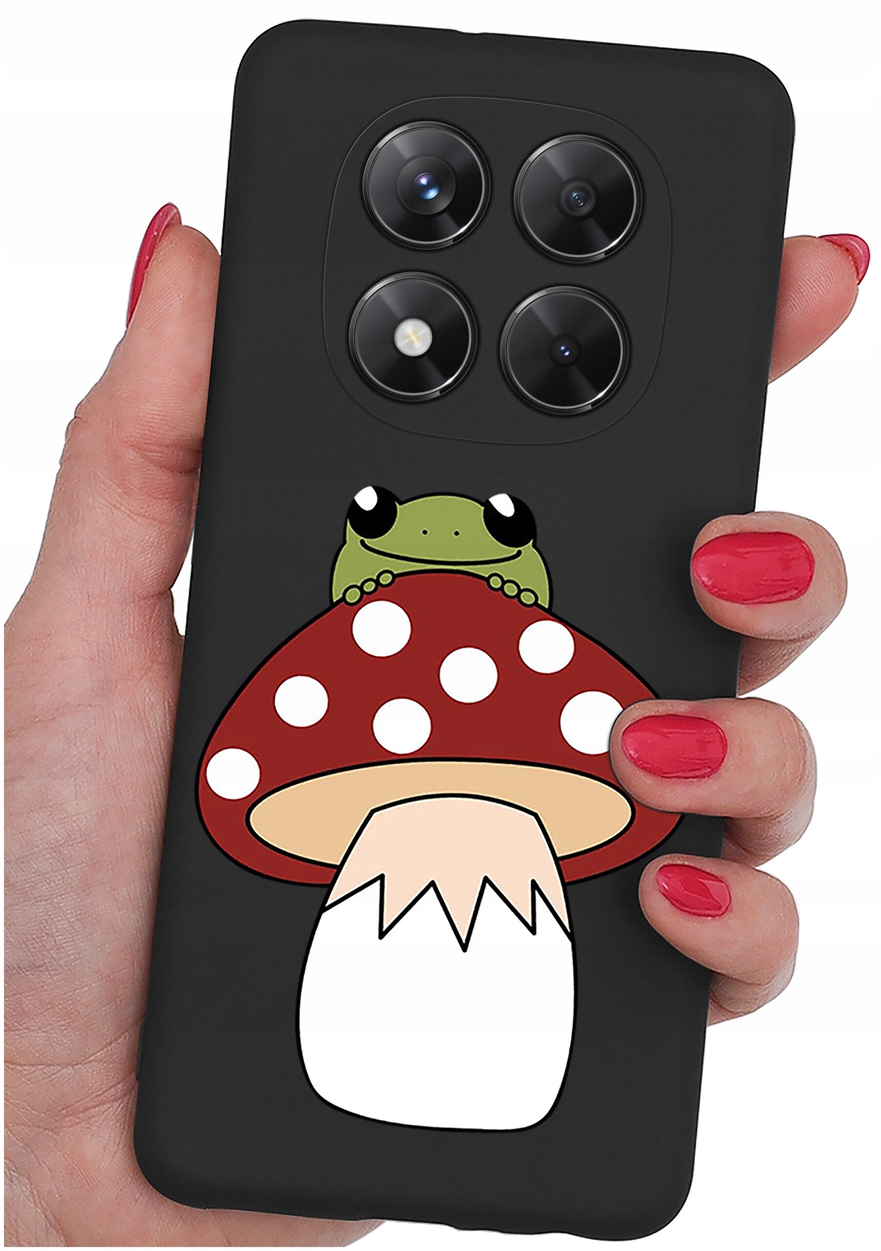Czarne etui na telefon z grafiką przedstawiającą żabę siedzącą na czerwonym muchomorze z białymi kropkami. Etui trzymane jest w dłoni z pomalowanymi na czerwono paznokciami.