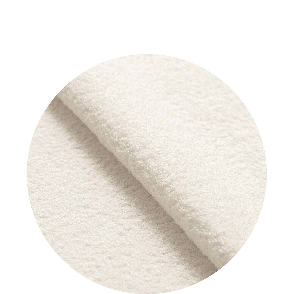 Obraz przedstawia zbliżenie na jasnobeżowy materiał o teksturze boucle teddy, widoczny w okrągłym kadrze.