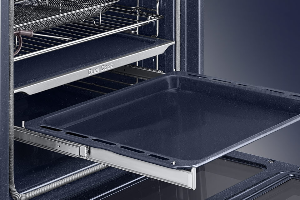 Wnętrze piekarnika z wysuniętą blachą i widocznym napisem \'Dual Cook\'. Piekarnik ma metalowe półki i ciemne wykończenie.