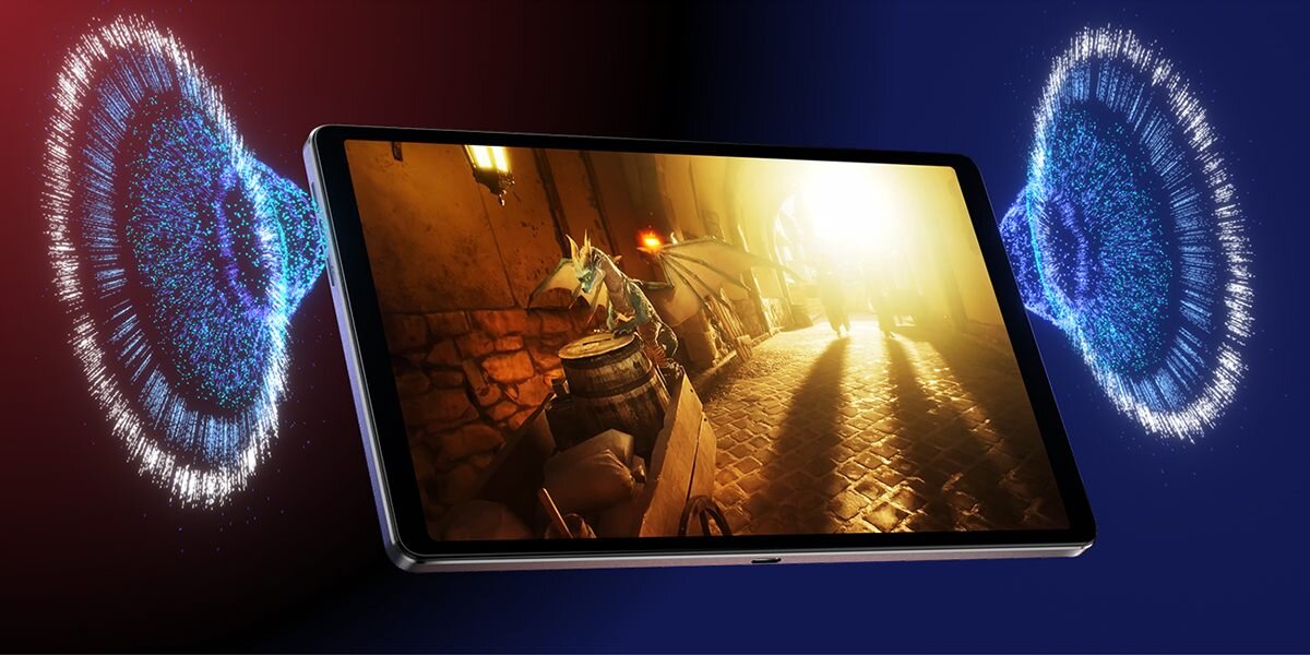 Tablet wyświetla scenę z gry, przedstawiającą oświetloną uliczkę z kamiennymi ścianami i beczkami. Po obu stronach tabletu widoczne są efekty graficzne przypominające fale dźwiękowe.