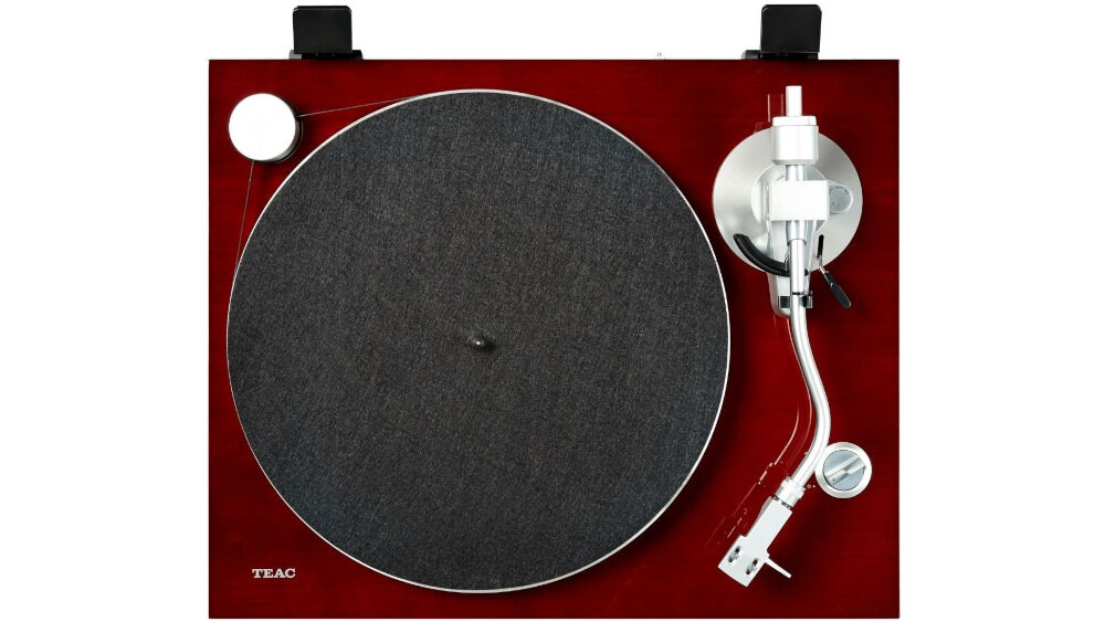 Gramofon z ciemnym talerzem i srebrnym ramieniem na tle wiśniowej obudowy. Widoczne logo: TEAC.