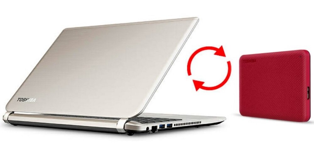 Obraz przedstawia otwarty laptop z logo \'TOSHIBA\' oraz czerwony dysk zewnętrzny z logo \'TOSHIBA\'. Pomiędzy nimi znajduje się symbol dwóch zakrzywionych strzałek wskazujących na wymianę danych.