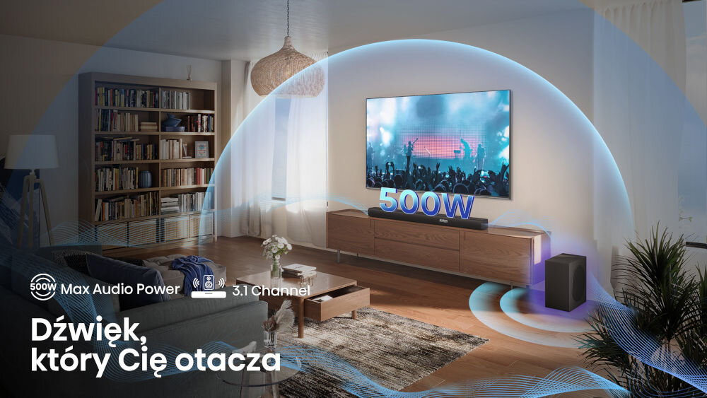 W salonie znajduje się telewizor z wyświetlanym koncertem, a przed nim soundbar i subwoofer. Na obrazie widoczny jest tekst: \'500W Max Audio Power, 3.1 Channel, Dźwięk, który Cię otacza\'.