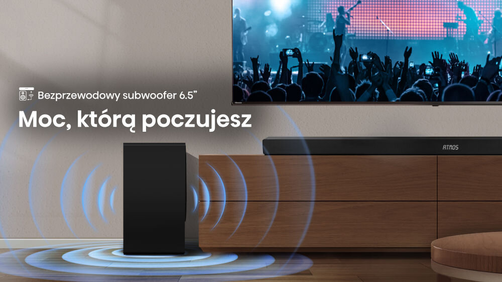 Na obrazie znajduje się czarny subwoofer obok drewnianej szafki, a nad nim widoczny jest telewizor z koncertem. Tekst na obrazie: \'Bezprzewodowy subwoofer 6.5\