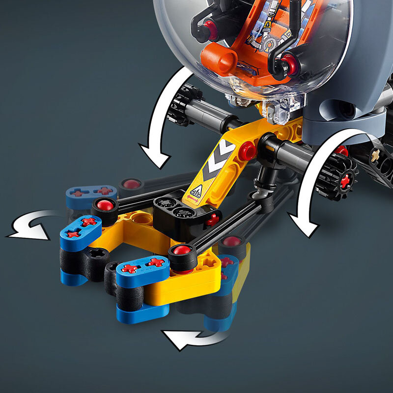 Obraz przedstawia fragment modelu LEGO z ruchomymi elementami w kolorach żółtym, niebieskim i czarnym, z widocznymi strzałkami wskazującymi kierunek ruchu. W tle znajduje się przezroczysta kopuła z elementami w kolorze pomarańczowym i czerwonym.
