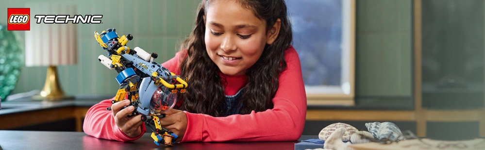 Dziecko bawi się kolorowym modelem z klocków LEGO. W lewym górnym rogu widoczne jest logo \'LEGO TECHNIC\'.