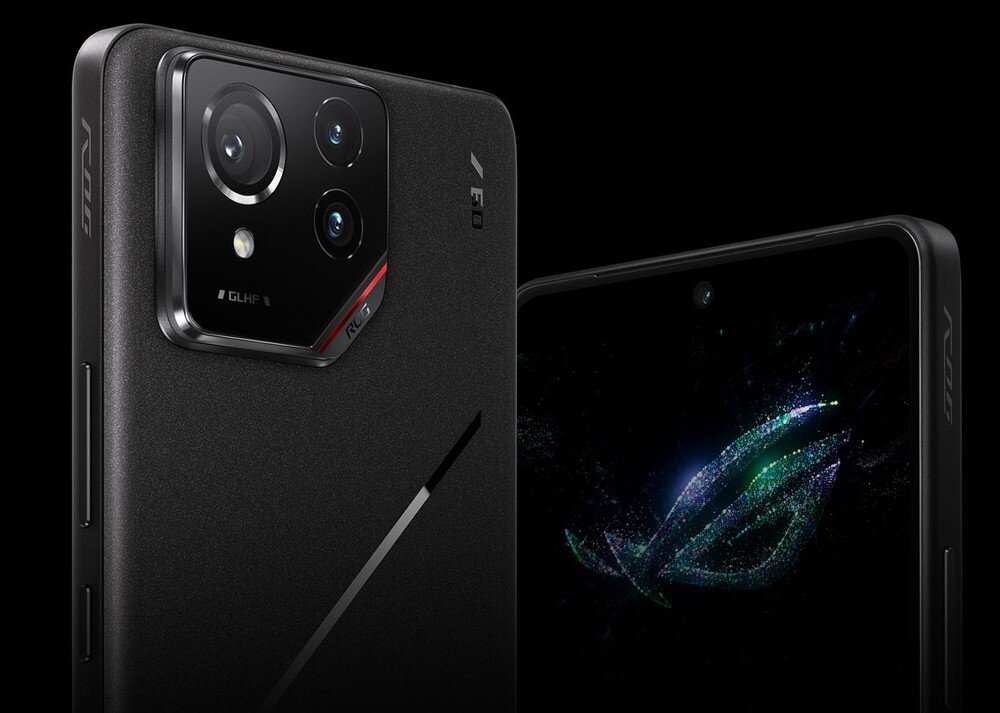 Obraz przedstawia czarny smartfon z widocznym modułem aparatu z trzema obiektywami i napisem \'ROG\'. Na ekranie telefonu widoczne jest kolorowe logo w kształcie litery \'R\'.