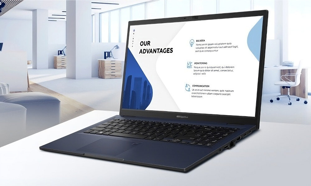 Laptop z otwartym ekranem wyświetlającym tekst \'OUR ADVANTAGES\' stoi na biurku w nowoczesnym biurze. W tle widać jasne wnętrze z biurkami i krzesłami.