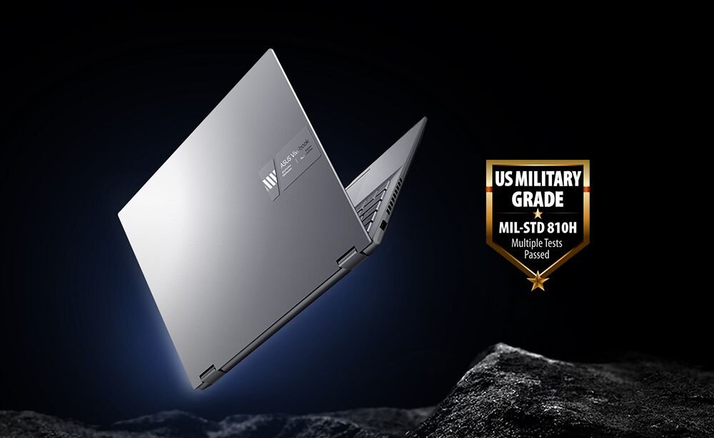 Srebrny laptop z logo ASUS na pokrywie, otwarty pod kątem, na ciemnym tle. Obok widoczna odznaka z napisem \'US MILITARY GRADE MIL-STD 810H Multiple Tests Passed\'.