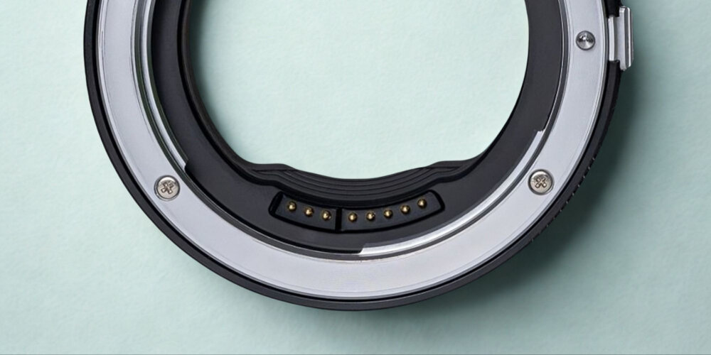 ADAPTER BAGNETOWY Z AUTOFOCUSEM MEGADAP EFTZ21 - CANON EF NIKON Z Zbliżenie na fragment metalowego adaptera bagnetowego z widocznymi stykami elektrycznymi i śrubami na jasnym tle