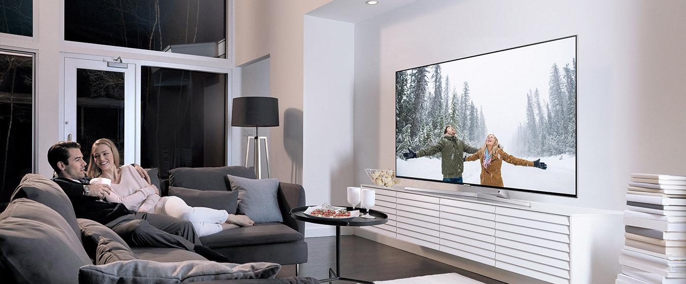 Wzornictwo: para siedząca na kanapie w salonie, czule obejmująca się i oglądająca swoje zdjęcia na SUHD TV