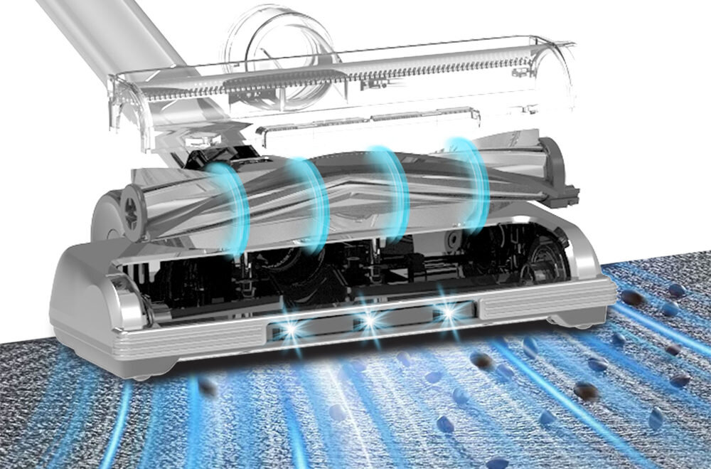 Obraz przedstawia dolną część odkurzacza z przezroczystą obudową, ukazującą mechanizm szczotki i przepływ powietrza oznaczony niebieskimi strzałkami. Na dywanie widoczne są cząstki brudu, które są zasysane przez odkurzacz.