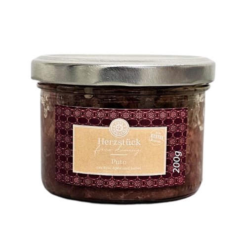 Słoik z metalową pokrywką zawiera produkt spożywczy, na etykiecie widnieje napis \'Herzstück Pute mit Reis, Apfel und Sellerie 200g\'.