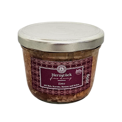 Słoik z metalową pokrywką zawierający produkt spożywczy, z etykietą w kolorze bordowym z białym tekstem: \'Herzstück fine Dining Ente mit Reis, Karotte, Banane und Kokos 200g\'.