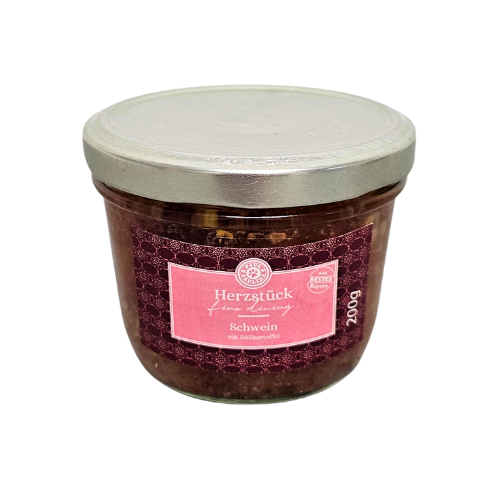 Słoik z metalową pokrywką zawiera produkt spożywczy z etykietą w kolorze różowym z napisem \'Herzstück fine dining Schwein mit Süßkartoffeln 200g\'.