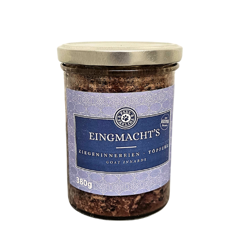 Słoik z metalową pokrywką zawiera produkt oznaczony etykietą z napisem \'EINGMACHT\'S ZIEGENINNEREREIEN - TOPFERL GOAT INNARDS\'. Na etykiecie widnieje również informacja \'380g\'.